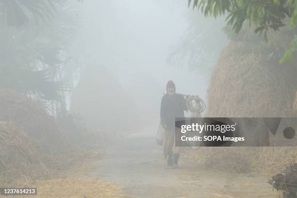 Man walks on the road during a cold and foggy morning.