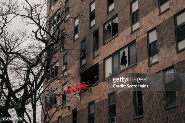 Broken windows and charred bricks mark the exterior of a 19-story residential building after a fire erupted in the morning on January 9, 2022 in the...