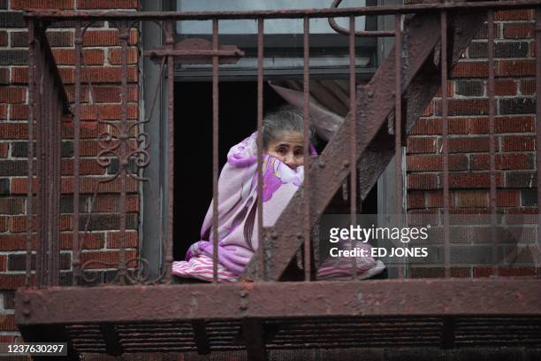 Neighbors watch firefighters from their windows after a deadly apartment fire in the Bronx, on January 9 in New York. - At least 19 people have died...