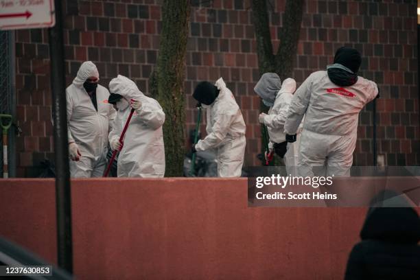 Workers clean debris at the scene after a fire at a 19-story residential building that erupted in the morning hours on January 9, 2022 in the Bronx...