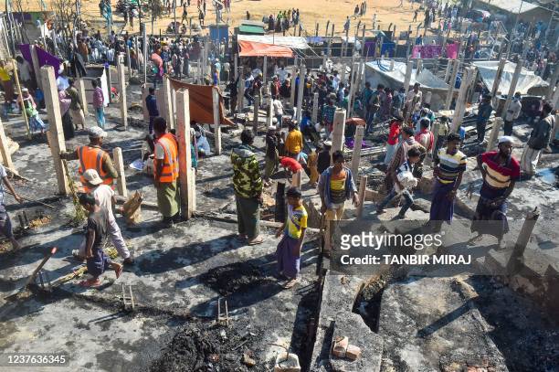 People gather on the ground of brunt-out houses a day after a fire gutted parts of a Rohingya refugee camp in Ukhia on January 10, 2022.