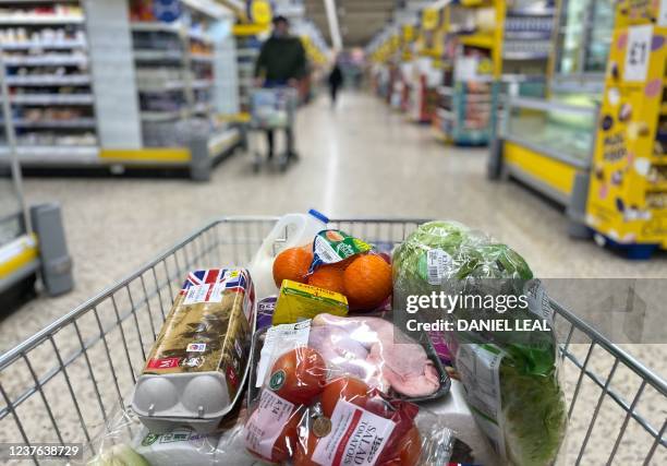 Food items are pictured loaded into a shopping trolley inside a Tesco supermarket store in east London on January 10, 2022. - UK annual inflation...