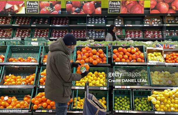 Customer shops for food items inside a Tesco supermarket store in east London on January 10, 2022. - UK annual inflation rocketed last November to...
