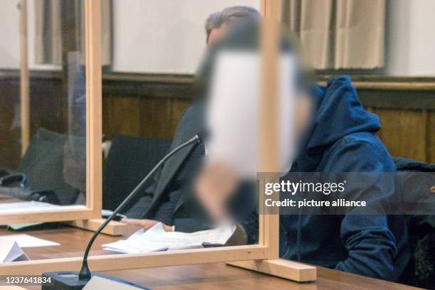January 2022, Lower Saxony, Aurich: A defendant holds a sheet of paper in front of his face at the beginning of a trial at Aurich Regional Court. The...