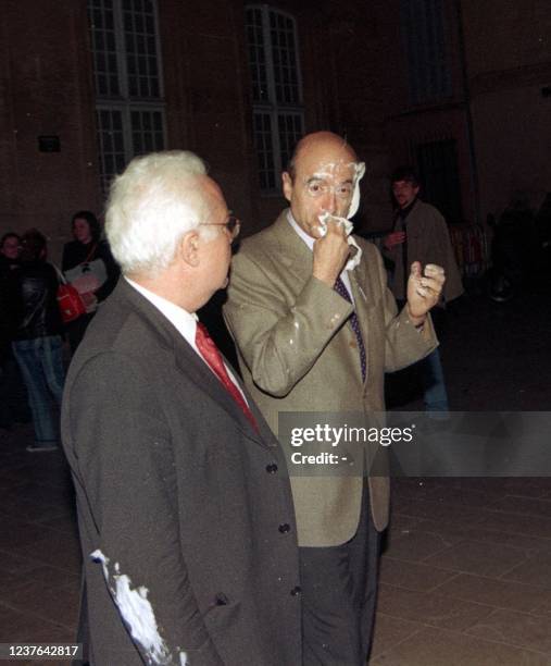 Alain Juppé, président de l'UMP, se nettoie le visage après s'être fait "entarter" le 19 Mars 2003 en quittant l'institut d'études politiques...