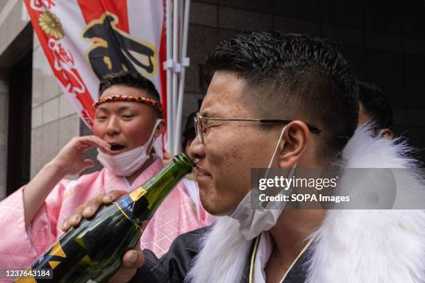 Participant drinks a bottle of alcohol before Seijinshiki in front of Yokohama Arena. The Japanese celebrate crossing the threshold into adulthood...