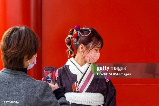 Mother takes photos of her daughter in traditional kimono as they visit Senso-ji temple to celebrate Seijin no Hi . Japanese people who have their...