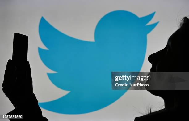 An image of a woman holding a cell phone in front of a Twitter logo displayed on a computer screen. On Tuesday, January 12 in Edmonton, Alberta,...