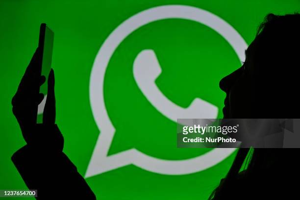 An image of a woman holding a cell phone in front of a WhatsApp Messenger logo displayed on a computer screen. On Tuesday, January 12 in Edmonton,...