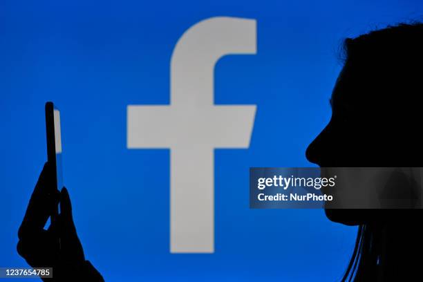 An image of a woman holding a cell phone in front of a Facebook logo displayed on a computer screen. On Tuesday, January 12 in Edmonton, Alberta,...