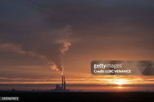 This picture taken on January 11, 2022 shows the sun rising over coal-fired powerplant of French multinational electric utility company EDF in...