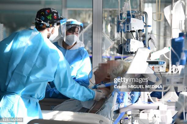 Medical staff members tend to a Covid-19 patient at the intensive care unit of Cremona hospital, in Cremona, northern Italy, on January 11, 2022. -...