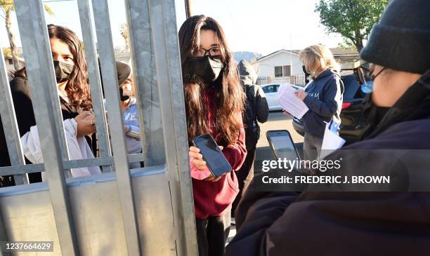 Students shows her negative Covid-test result from her cellphone for entry to Olive Vista Middle School on the first day back following the winter...