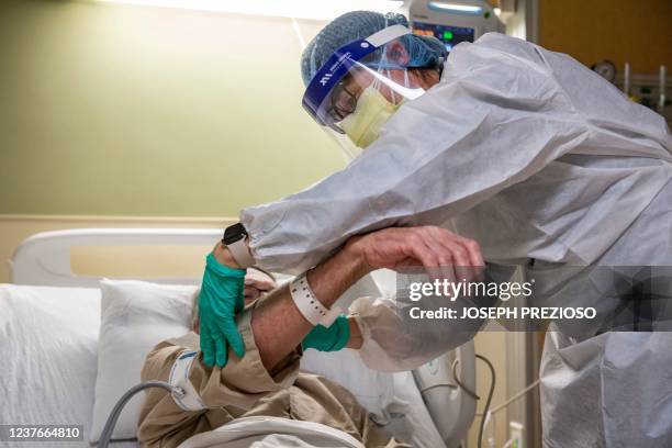 Army veteran with Covid-19 is treated by a medical worker in a negative pressure room in the Covid-19 ward at the US Department of Veterans Affairs...