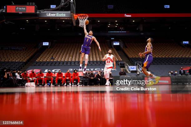 Devin Booker of the Phoenix Suns dunks as Fred VanVleet of the Toronto Raptors and Mikal Bridges of the Phoenix Suns trail behind during the first...