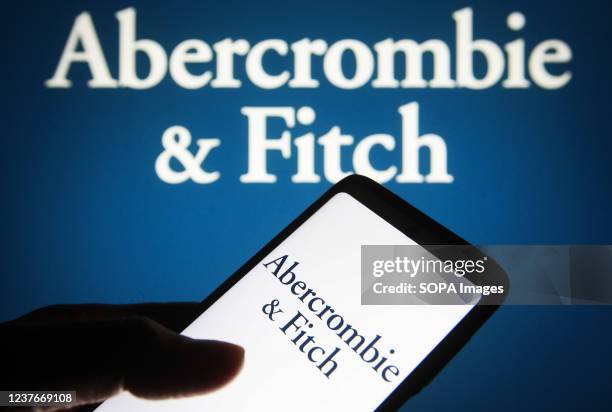 In this photo illustration, the Abercrombie & Fitch logo is seen on a smartphone screen and in the background.