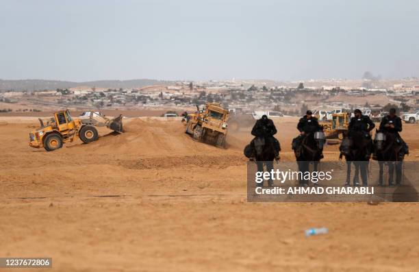 Israeli mounted police stand guard as excavators work during a protest by Bedouins in the southern Israeli village of Sawe al-Atrash in the Neguev...