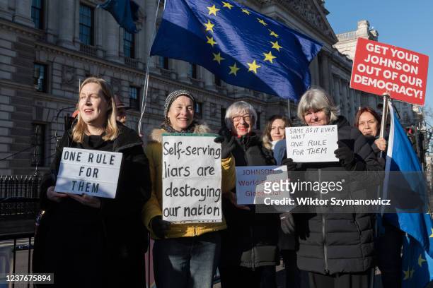 Demonstrators hold placards outside Houses of Parliament as British Prime Minister Boris Johnson attends the weekly PMQs in the Commons on January...