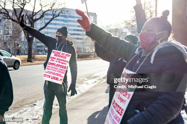 King Soopers grocery store worker Lawrence Kelly, left, waves at passing drivers as he joins his fellow union members as they strike across the...