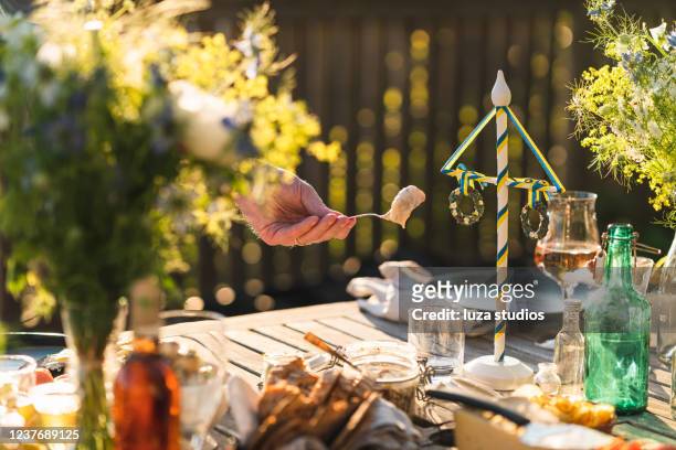 man taking herring at midsummer dinner party - mid summer stock pictures, royalty-free photos & images