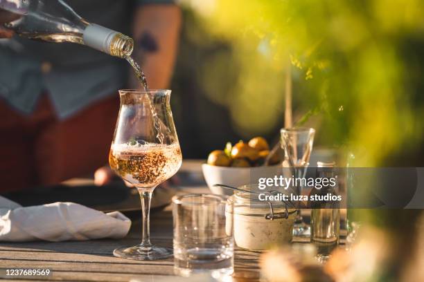 hombre vertiendo vino rosado en la cena de verano - vino rosado fotografías e imágenes de stock