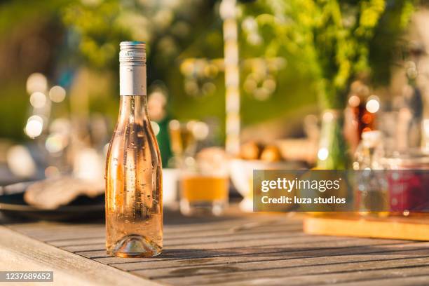 fles koude roze wijn op midzomerdinerlijst - wijn tuin stockfoto's en -beelden