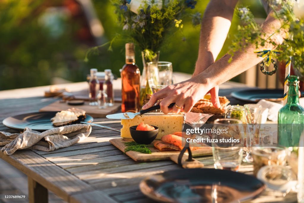 Man taking a slice of cheese at midsummer dinner