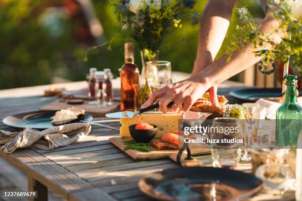 man taking a slice of cheese at midsummer dinner - solstice stock pictures, royalty-free photos & images