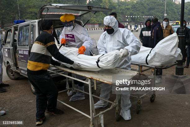 Volunteers in personal protective equipment take out from a hearse the body of a person who died due to the Covid-19 coronavirus, at a cremation...