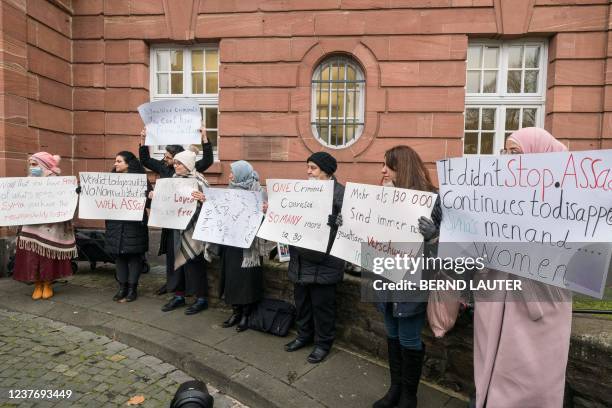 People hold posters during a demonstration outside the courthouse where former Syrian intelligence officer Anwar Raslan stood on trial in Koblenz,...