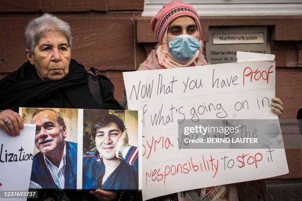 Women hold posters and photographs during a demonstration outside the courthouse where former Syrian intelligence officer Anwar Raslan stands on...