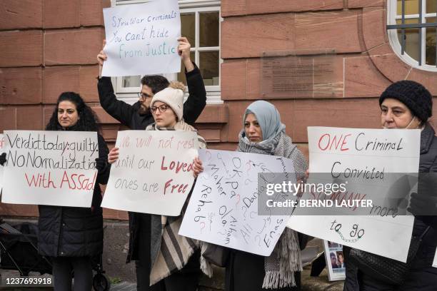 People hold posters during a demonstration outside the courthouse where former Syrian intelligence officer Anwar Raslan stood on trial in Koblenz,...