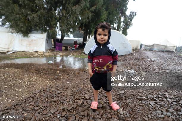 Syrian child stands in front of a tent at the flooded al-Balea camp for internally displaced persons near Jisr al-Shughur in Syria's northwestern...