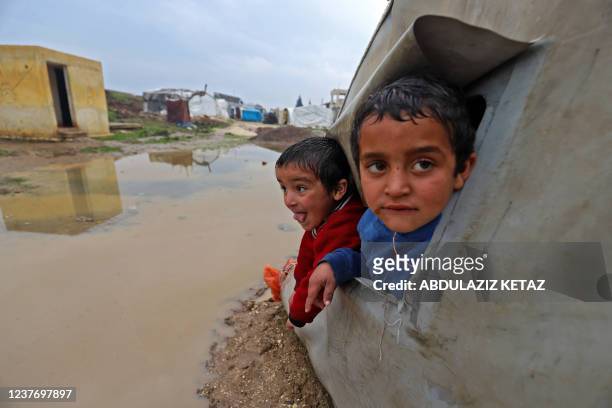 Syrian children look over a puddle of water in the flooded al-Balea camp for internally displaced persons near the city of Jisr al-Shughur in Syria's...
