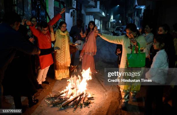 People dance and throw seeds and candies into the Lohri bonfire during Lohri festival celebration at Laxmi Garden near Khandsa road, on January 13,...