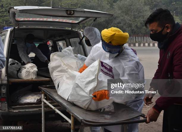 Shaheed Bhagat Singh Sewa Dal volunteers in personal protective equipment take out from a hearse the body of a person who died due to the Covid-19...