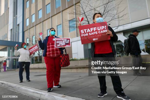 Registered nurses Tricia Nunn, center, and Marilyn Mirafelix, right, take part in a rally outside the Kaiser Permanente Oakland Medical Center on...