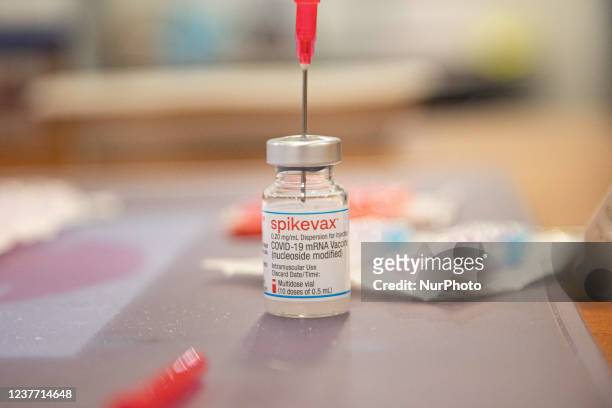 Close-up at a vial with a needle and the booster inscription. GGD public medical healthcare worker prepares the Moderna Spikevax mRNA Covid-19...