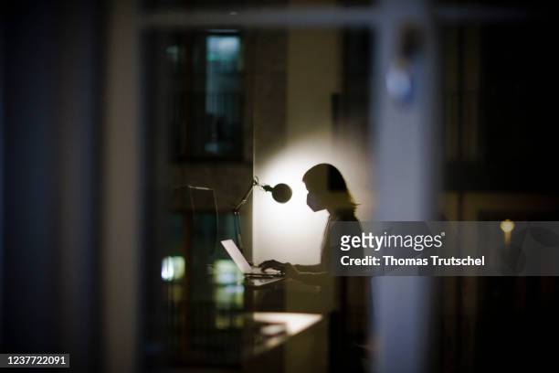 Symbolic photo on the topic of masks in the workplace. A woman sits at her office desk in the evening and wears an FFP2 mask on January 14, 2022 in...