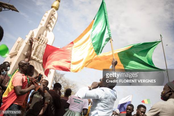 Men wave Malian national flags during a mass demonstration in Bamako, on January 14 to protest against sanctions imposed on Mali and the Junta by the...