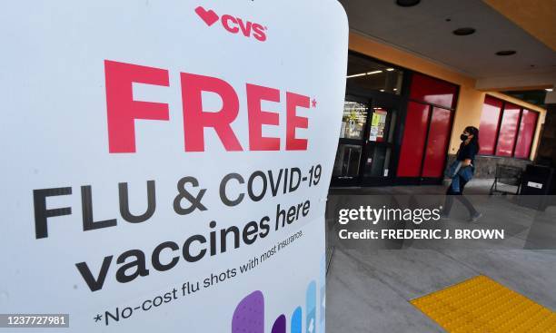 Woman arrives at a CVS pharmacy past a sign about free flu and Covid-19 vaccines on January 14, 2022 in Monterey Park, California. - Americans can...