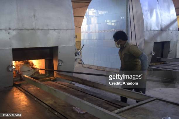 Crematorium staff checks a burning pyre of a Covid-19 victim at Nigambodh Ghat crematorium in New Delhi, India on January 15, 2022. India reported...