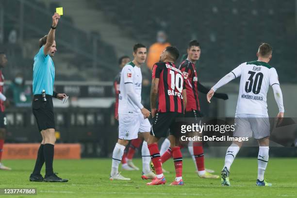 Referee Sascha Stegemann shows Kerem Demirbay of Bayer 04 Leverkusen the yellow card during the Bundesliga match between Borussia Mönchengladbach and...