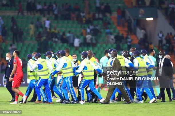 Stewards escort the referees of the pitch after the Group D Africa Cup of Nations 2021 football match between Guinea-Bissau and Egypt at Stade Roumde...