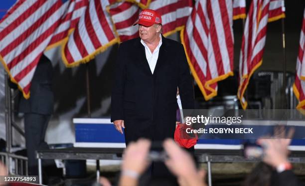 Former US President Donald Trump holds MAGA hats for his supporters, as he arrives to speak at a rally at the Canyon Moon Ranch festival grounds in...