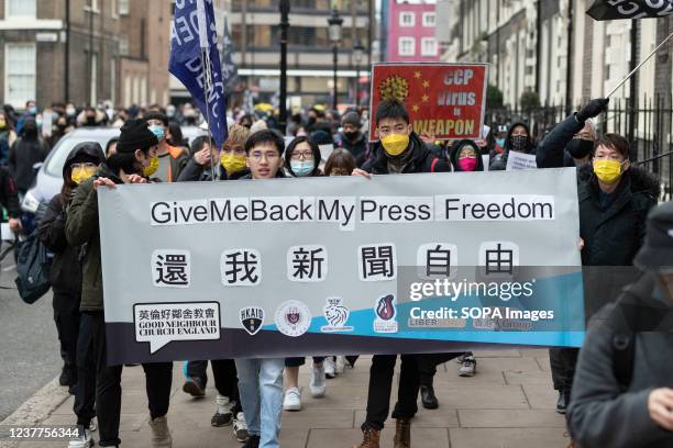 Protesters march with a banner, saying "Give me back my press freedom" during the demonstration. Hongkongers in London gather at Piccadilly Circus to...