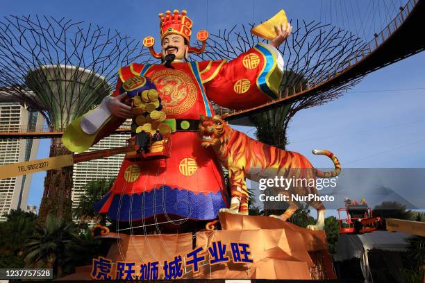 Workers put up decorative gold coins on a giant lantern display featuring the God of Fortune next to a tiger as Singapore prepares to usher in the...