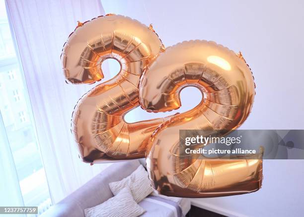 January 2022, Berlin: ILLUSTRATION - Two golden balloons in the shape of the number 2 hang in a room. In February this year there are several days...