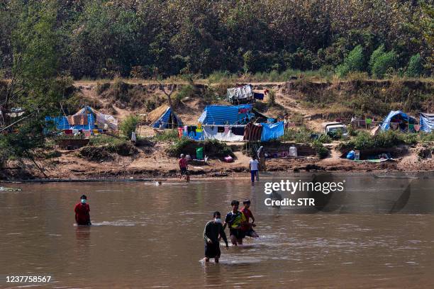 This photo taken on January 15, 2022 shows Myanmar refugees, who fled a surge in violence as the military cracks down on rebel groups, walking across...