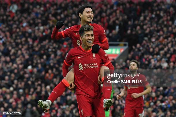 Liverpool's Japanese midfielder Takumi Minamino jumps on the back of Liverpool's Brazilian midfielder Roberto Firmino as he celebrates scoring his...